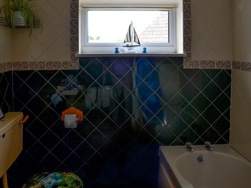 Isle Brewers罗塞特东翼度假屋的带浴缸的浴室和带帆船的窗户