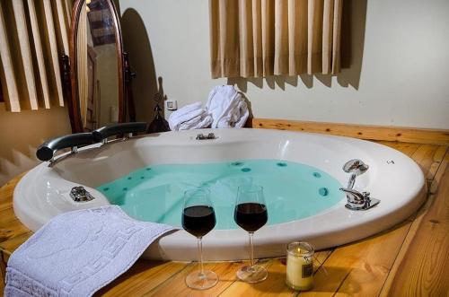 Mishmār Hāyardinאתנחתא בירדן的浴缸配有两杯红葡萄酒