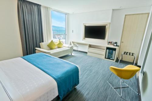 布卡拉曼加Sonesta Hotel Bucaramanga的酒店客房配有床、沙发和电视。