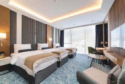 波德戈里察Bristol Hotel Podgorica的酒店客房设有三张床和一张书桌