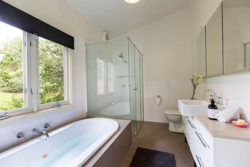 诺拉Nowra Beauty的带浴缸、卫生间和窗户的浴室