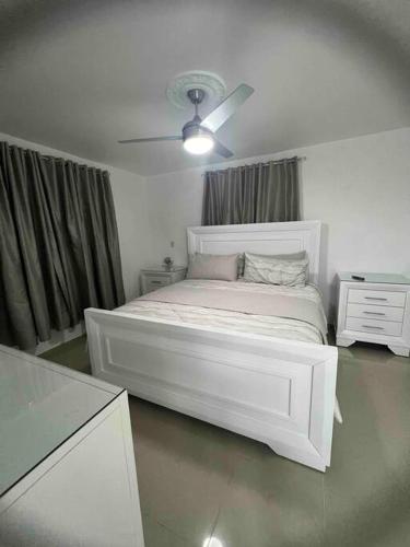 圣地亚哥洛斯卡巴Residencial joyas d’ luxe lll的白色卧室配有床和吊扇
