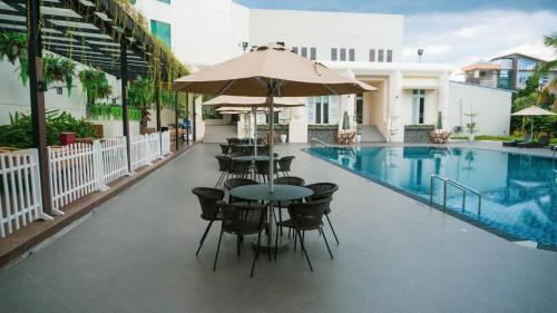 棉兰埃默拉尔德花园国际酒店的一个带桌椅的庭院和一个游泳池