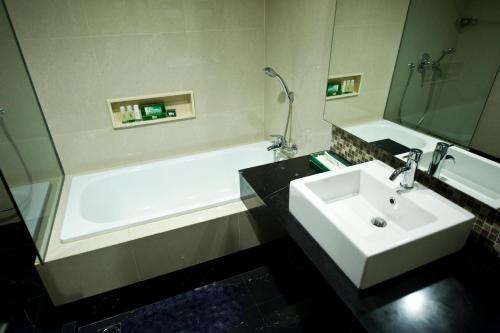 棉兰埃默拉尔德花园国际酒店的浴室配有白色水槽和浴缸。