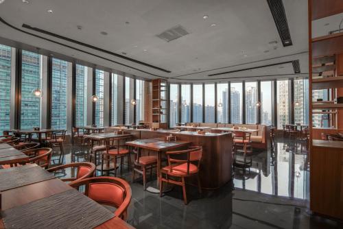 广州广州珠江新城华轩里酒店的餐厅设有桌椅和高高的窗户。