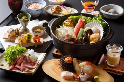 阿寒湖畔阿寒河拉维斯塔温泉酒店的餐桌上放有食物盘子和一碗寿司