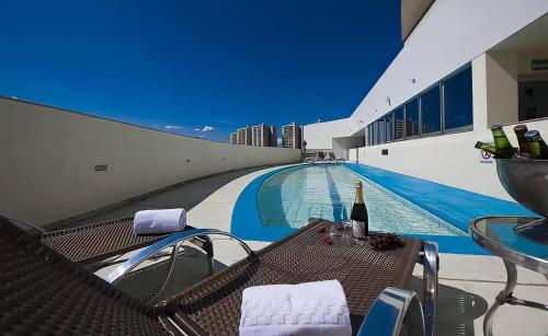 巴西利亚Unidade Executiva Luxo 33m²的一个带桌子和一瓶葡萄酒的游泳池
