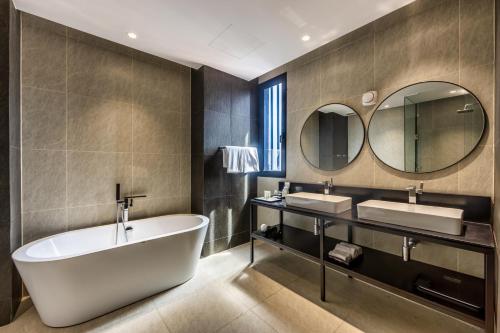 金边Luxcity Hotel & Apartment的带浴缸、两个盥洗盆和镜子的浴室