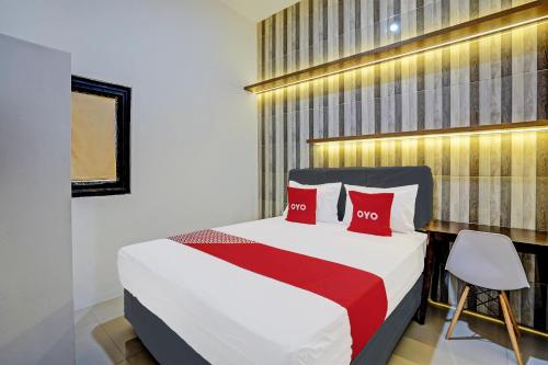 泗水OYO 92435 Sunlo Cozy Home Family Homestay Syariah的一间卧室配有一张带两个红色枕头的床