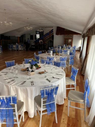 Hanul Marioarei的宴会厅配有白色的桌子和蓝色的椅子