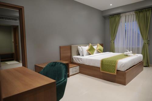阿勒皮Hotel Grand Alleppey的一间卧室配有一张床、一张桌子和一把椅子