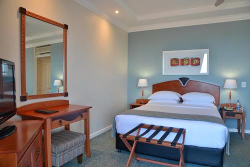 伊丽莎白港Courtyard Hotel Gqeberha的一间卧室配有一张床、一张书桌和一面镜子