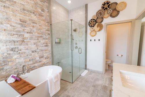 帕尔默Colony Suites的浴室配有白色浴缸和玻璃淋浴间。