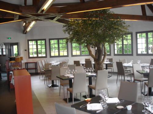 茹埃莱图尔湖餐厅酒店的用餐室配有桌椅和一棵树