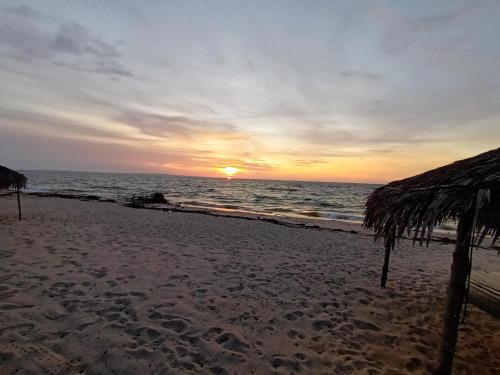 马哈赞加Akwaba Chez les Filles的海滩上的日落和稻草伞