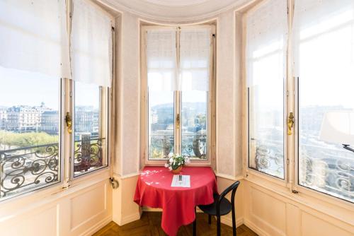 日内瓦城堡酒店的一间设有红色桌子、椅子和窗户的客房