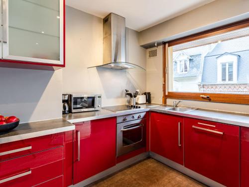 多维尔Apartment Les Cigognes by Interhome的一间厨房,配有红色橱柜和窗户