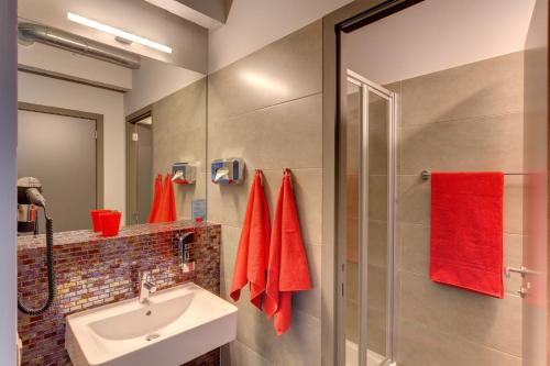 布鲁塞尔MEININGER Hotels Bruxelles City Center的浴室配有水槽和带红色毛巾的淋浴