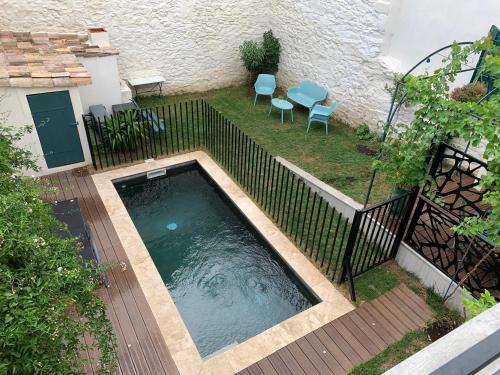 尼姆Agréable maison de ville clim/piscine/jardin的庭院内的游泳池,配有两把椅子和围栏