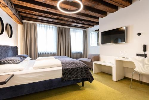 萨尔茨堡Boutiquehotel am Dom的一间卧室配有一张床、一张书桌和一台电视。