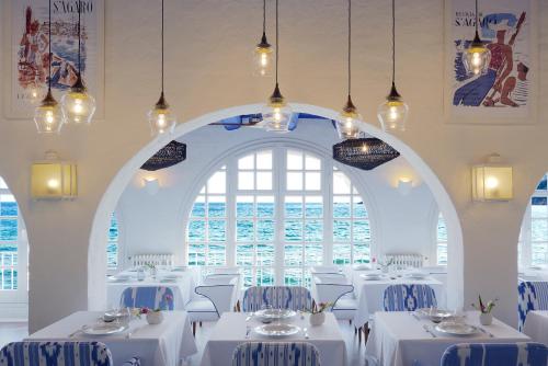 萨卡罗Hostal de la Gavina GL - The Leading Hotels of the World的一间设有白色桌子和大窗户的用餐室