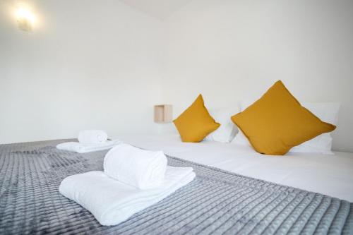 阿尔布费拉Oura Parque Apartamentos Turisticos的一张带白色毛巾和黄色枕头的床