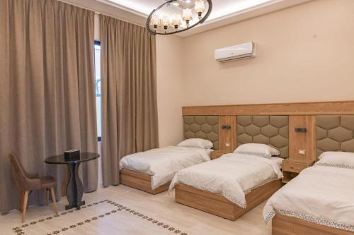 索瓦马Adam's Luxury Villa DeadSea的一间卧室配有两张床、一张桌子和一把椅子