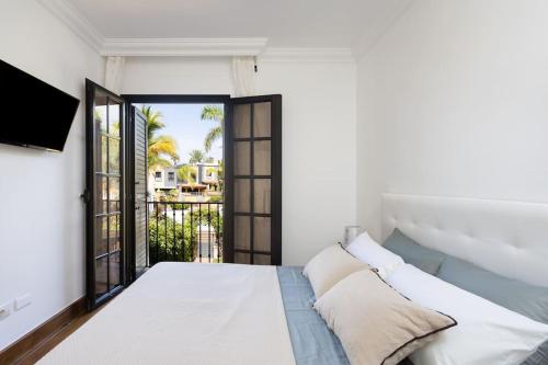 阿德耶Villa esclusiva a 300m da Playa del Duque的一间白色卧室,配有床和阳台
