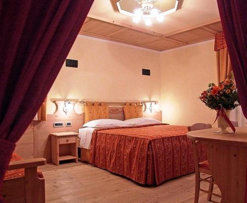 迪马罗Jolly B&B - Affittacamere的一间卧室配有一张床和一张鲜花桌