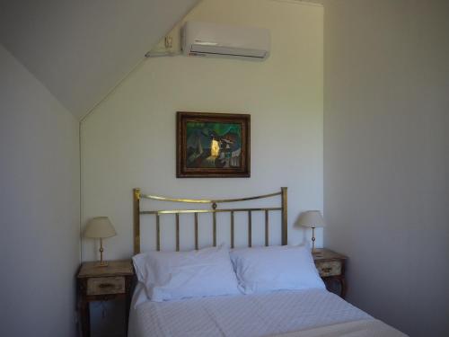 迈普Villa Victoria Lodge的卧室内的一张床位,配有两张桌子和一张墙上的照片
