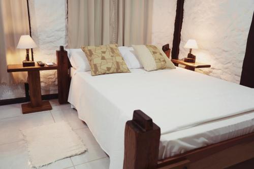 布卢梅瑙Sítio Urbano a apenas 1,5 km do centro的一间卧室配有一张带两盏灯的大型白色床。