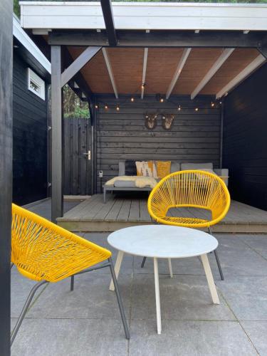 鹿特丹Sfeervol guesthouse, privé tuin en free parking的天井上配有2把黄色椅子和1张桌子