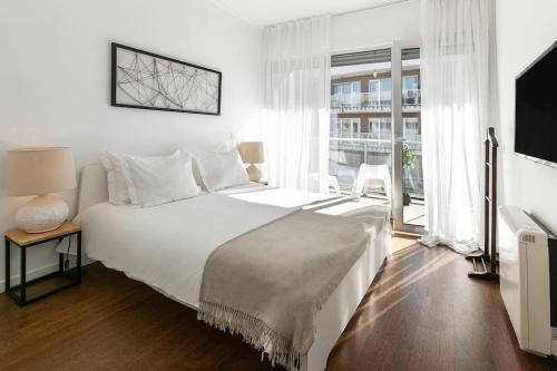 里斯本Lisbon Metro & Pool Apartment的白色的卧室设有一张大床和一个窗户