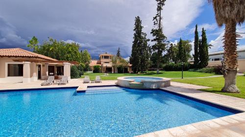 门多萨Casa Agostino - Luxury wine and hotel in Bodega Agostino的一个带椅子的庭院和房子的游泳池