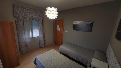 巴切诺Albergo Valentini的一间带两张床和吊灯的小卧室