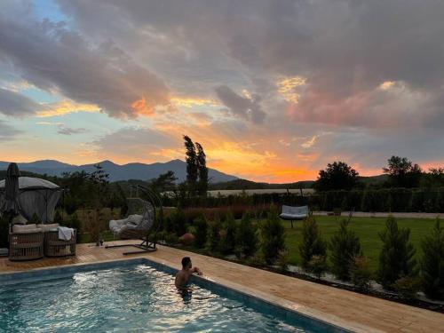 Manolya villa的游泳池里的人,背景是日落