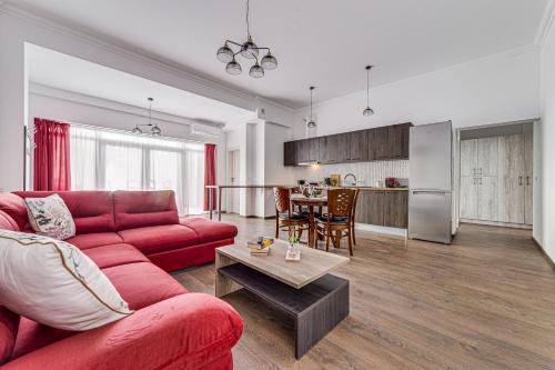 阿拉德ARI Central Grand Apartment的一间带红色沙发的客厅和一间厨房