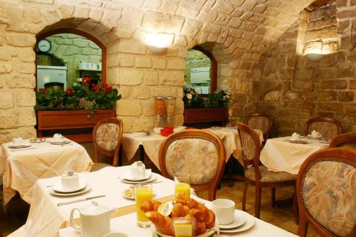 巴黎梅斯雷共和酒店的餐厅配有白色的桌椅,提供食物