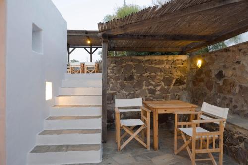 特里皮蒂Marketos Windmill and Houses的一个带桌椅和石墙的庭院