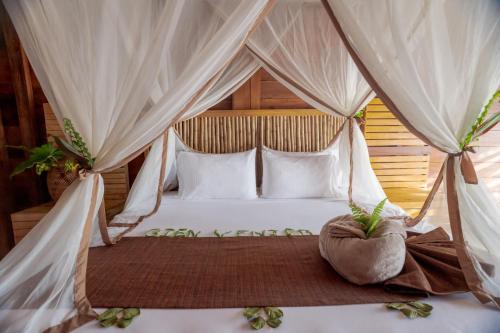 莱蒂西亚Biohotel Arara River的卧室配有带白色枕头的天蓬床