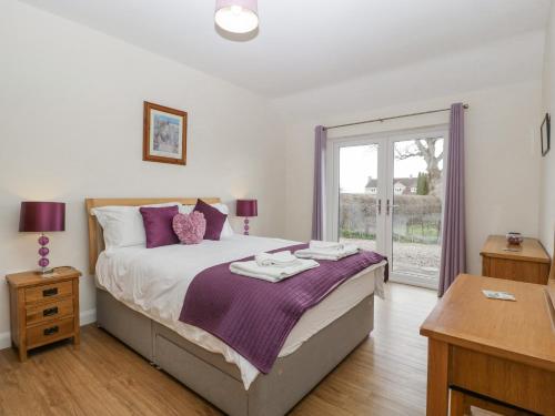 Queen CamelRectory Farm Lodge的一间卧室配有一张带紫色枕头的大床