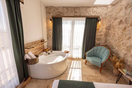 乌奇希萨尔Soleado Cappadocia Hotel的一间带浴缸的浴室和一把椅子