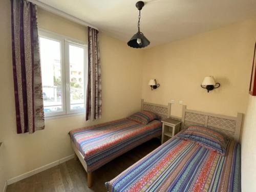 马莱莫尔Maison 3 pièces domaine golf Pont Royal的一间卧室设有两张床和窗户。