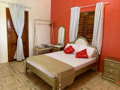 帕拉库鲁Happy Hostel e Pousada Paracuru的一间卧室配有一张带红色枕头和镜子的床