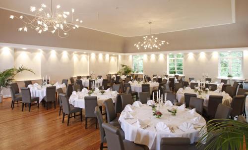 汉恩明登Hotel Schlafschön的宴会厅配有白色的桌椅和吊灯。