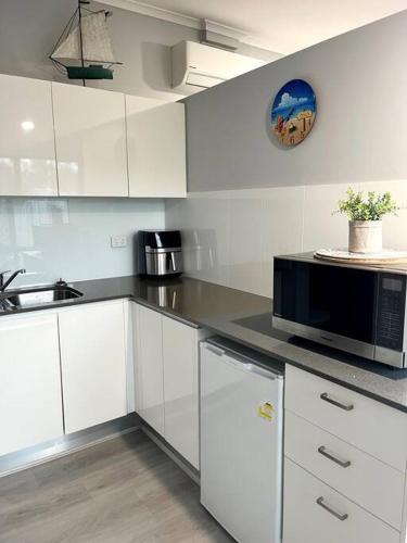 UranganSnapper Villa - Seaside的厨房配有白色橱柜和黑微波炉