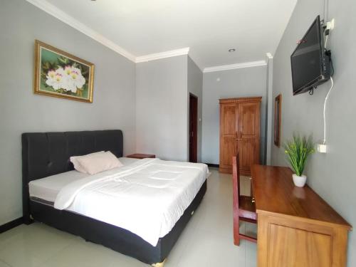 普禾加多Hotel Asri Baru的一间卧室配有一张床和一台平面电视