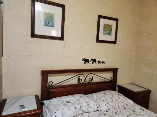 Għajn il-KbiraBest Relax in the best part of Gozo your own bedroom with Ensuite Toilet and Shared Pool Bed and Breakfast的卧室配有一张床,墙上挂有两张照片
