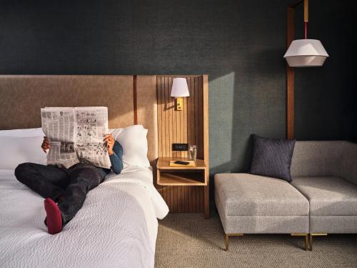 罗斯芒特Holiday Inn Chicago O'Hare - Rosemont, an IHG Hotel的躺在床上看报纸的人