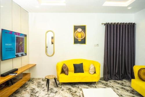 拉各斯Elegant 1-Bed With Unlimited Internet + 24hrs POWER的客厅设有黄色沙发和电视